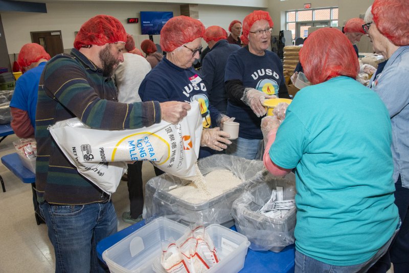 Nathan Kingree, left, refills the rice container at a filling station, Michele Cavanaugh and Don Peterson continue filling bags.